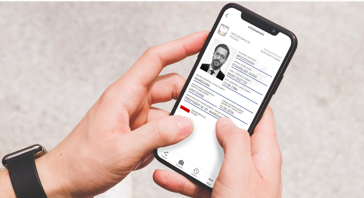 Na zdjęciu widać dłonie trzymające telefon, na którego wyświetlaczu widać aplikację m-Obywatel.