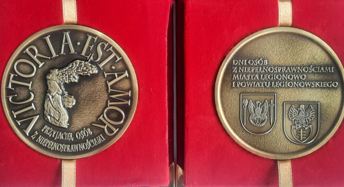 Na zdjęciu awers i rewers medalu Przyjaciel Osób z Niepełnosprawnościami. Medal w kolorze starego złota na czerwonym, aksamitnym tle.