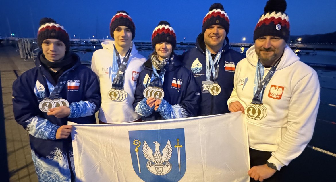zawodnicy UKS „Delfin” Legionowo  z flagą z herbem powiatu w dłoniach i medalami na szyi