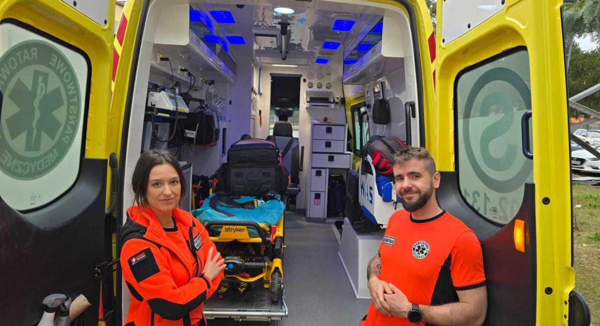 karetka, otwarte wnętrze, dwoje ratowników po bokach
