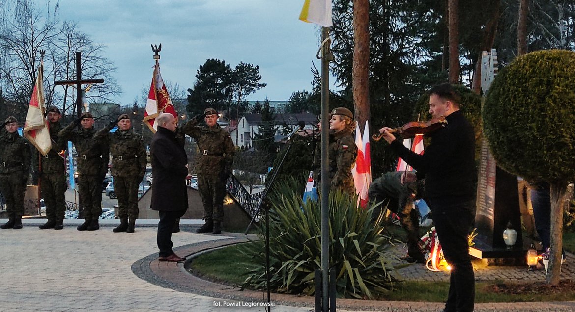 poczty sztandarowe i delegacja wicestarosty przed pomnikiem ofiar katynia, przy pomniku gra skrzypek