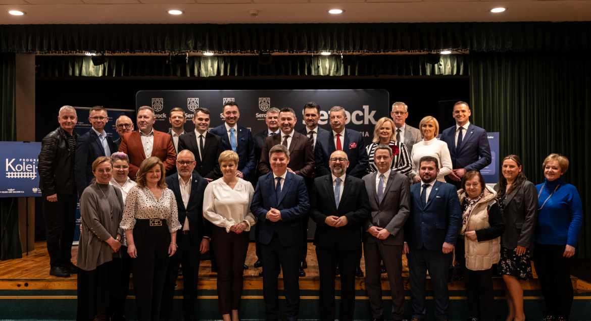 Zdjęcie grupowe przedstawiwa kilkanascie osób pozujących na sciance promocyjnej Miasta i Gminy Serock. Fot. UMiG Serock