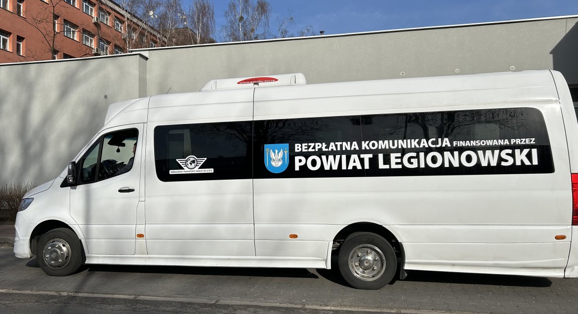 Biały autobus bezpłatnej komunikacji Powiatu Legionowskiego stojący na przystanku pod Starostwem