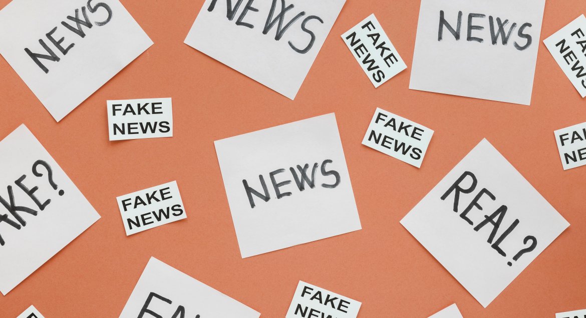 na pomarańczowym tle karteczki z napisem news, fake news oraz real?