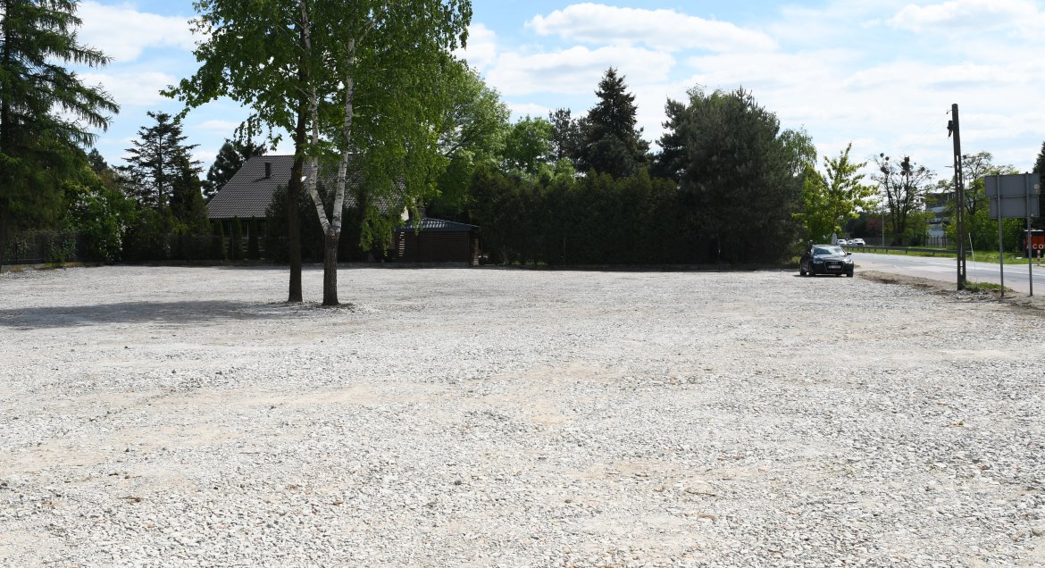 Zdjęcie przedstawia widok na nowo powstaly parking wyłożony tłuczniem betonowym.