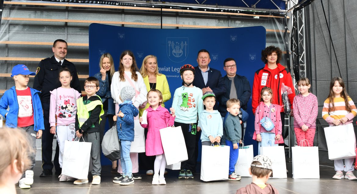 Na zdjęciu grupa dzieci i osoby nagrodzone podczas Pikniku Bezpieczny Powiat oraz przedstawiciele władz samorządowych na scenie