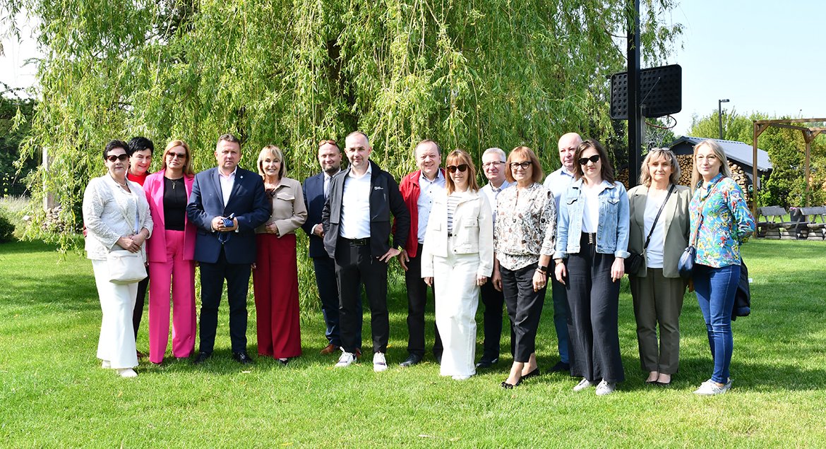 Zdjęcie grupowe przedstawiciel Powiatu Legionowskiego oraz Powiatu Dzierżoniowskiego, wykoane w plenerze na tle zieleni.
