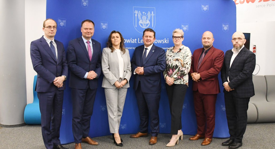 Na zdjęciu starosta legionowski, członkowie zarządu, skarbnik Powiatu i sekretarz Powiatu pozujący na tle błękitnej ścianki promocyjnej