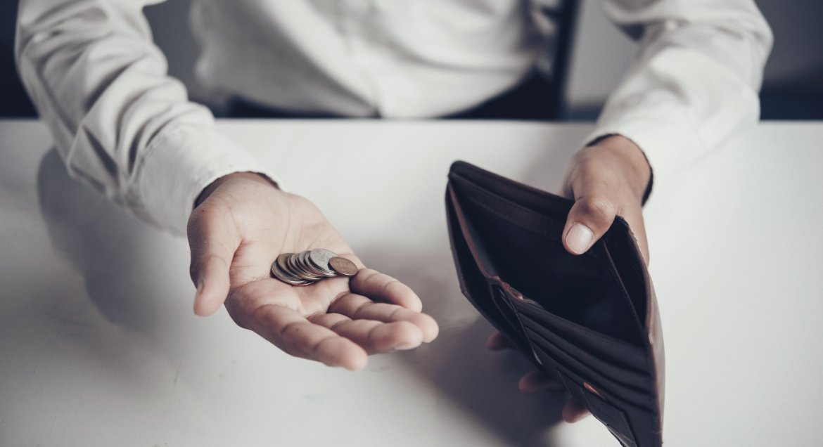 Na zdjęciu otwarty portfel i dłoń z monetami