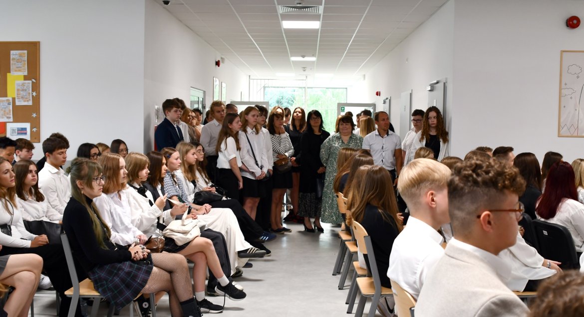 Zdjęcie wykonano podczas rozpoczecia roku w LO im. Stanisława Lema. Na korytarzu młodziez oraz nauczyciele i goście w odświętnych strojach.