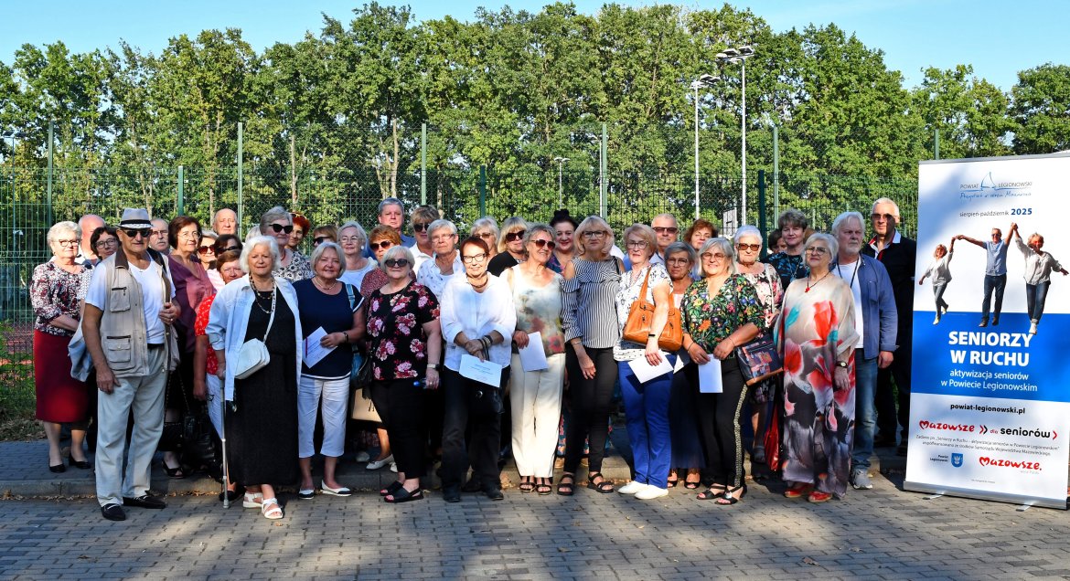 Zdjęcie grupowe seniorów na dworze, z boku rollup