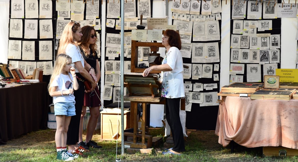 Stosko na fastiwalu, wystawa prac pod namiotami, rozmawiający ludzie