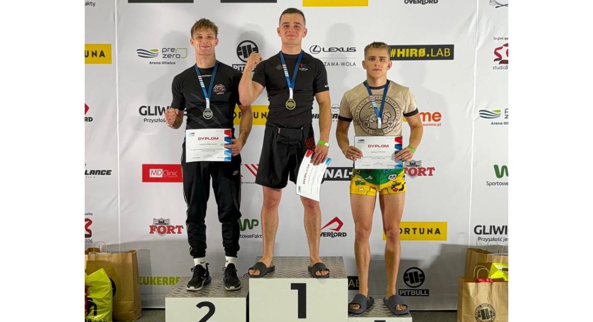 Na zdjęciu trzech młodych mężczyzn stojących na stopniach podium.