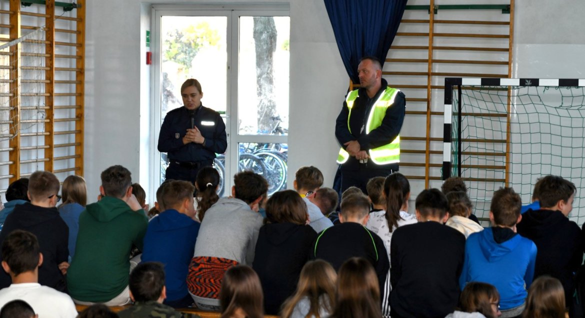 Spotkanie na sali gimnastycznej, dwójka policjantów przemawia do dzieci