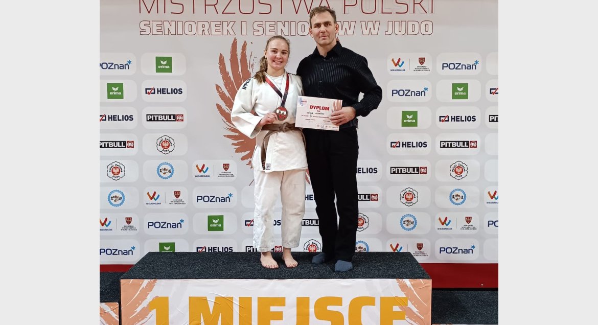Zdjęcie: na podium stoją: trzymające medal i dyplom judoczka Oliwia Kuźmińska (z lewej), z trenerem Jackiem Kuźmińskim (z prawej).