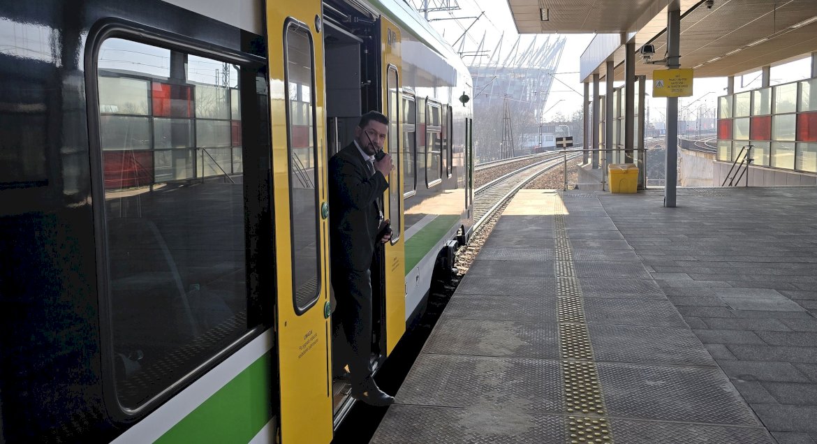 Na zdjęciu widać konduktora stojącego w drzwiach pociągu