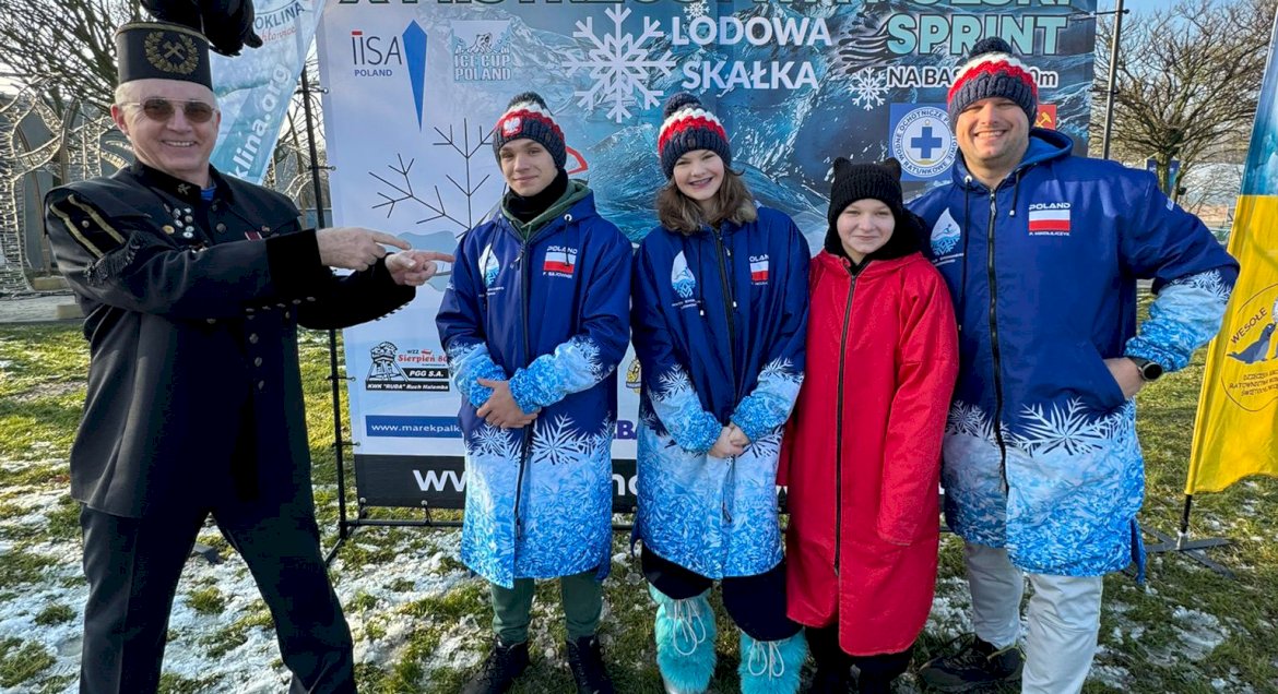 pływacy na tle ścianki z zawodów, obok górnik