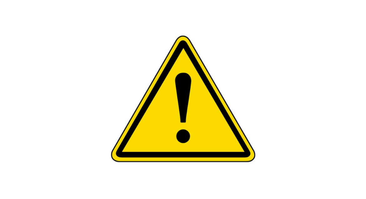 Żółty znak drogowy w kształcie trójkąta z czarnym wykrzyknikiem