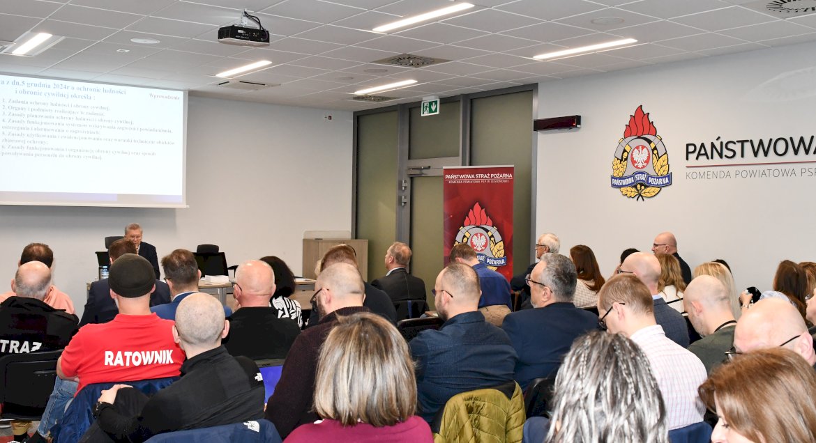 Osoby siedzące i sluchajace prelekcji na sali wykładowej w Komendzie Powiatowej Strazy Pożarnej w Legionowie