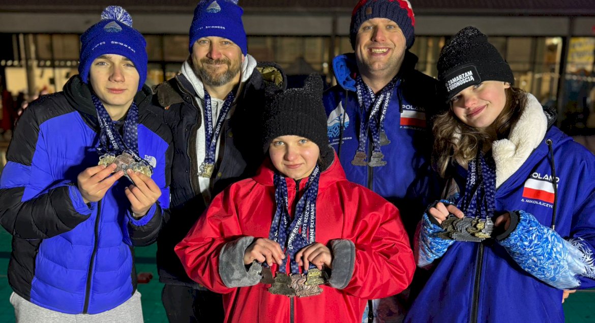 Na zdjęciu widać dwóch mężczyzn, jednego młodego chłopca i dwie dziewczynki, wszyscy ubrani w zimowe niebieskie bądź czerwone stroje z medalami na szyjach
