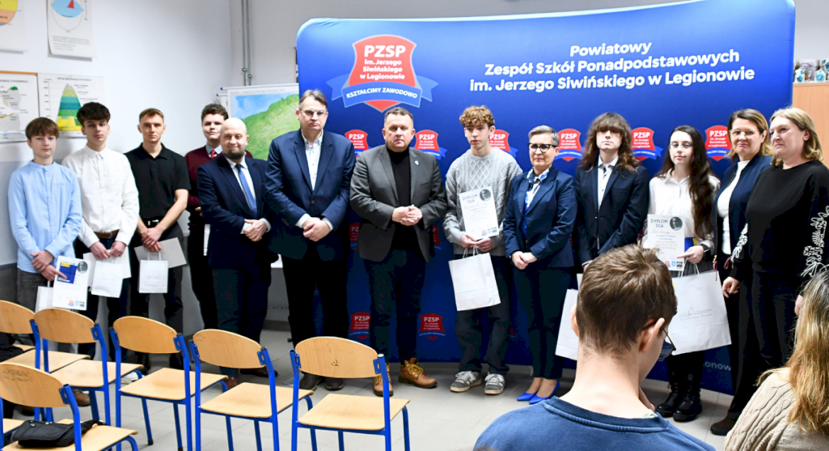 Na zdjęciu widać jak stoją w rzędzie laureaci ogólnopowiatowego konkursu historycznego oraz przedstawiciele szkoły i członkowie Zarządu Powiatu Legionowskiego
