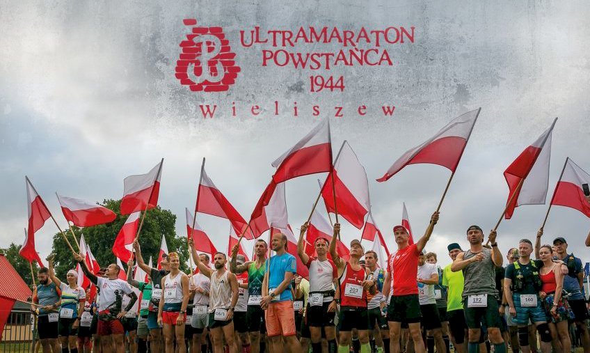 zdjęcie uczestników biegu z flagą, a u góly logo biegu