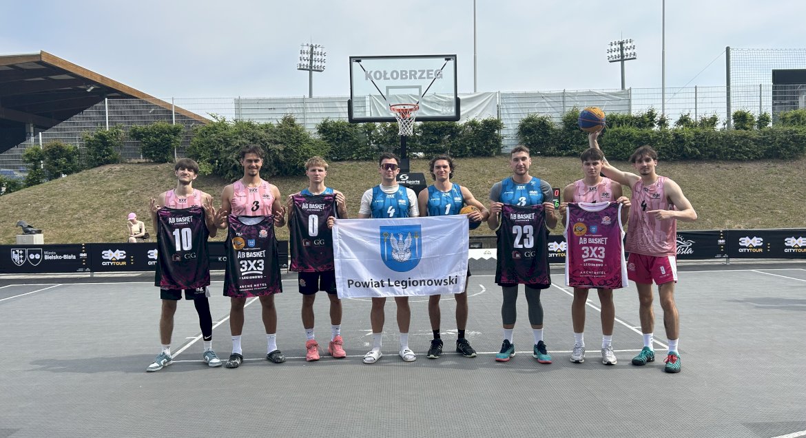 Zdjecie zawodsników drużyny AB Basket Legionowo z flagą Powiatu Legionowskiego