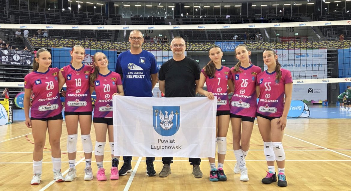 Zawodniczki z trenerem i flagą Powiatu
