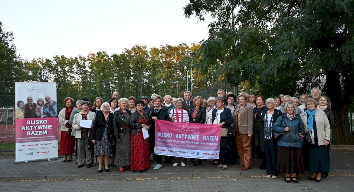 Zdjęcie grupowe - uczestnicy wyjazdu pozuja z bannerem projektu oraz rolupem