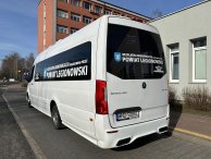 Zdjecie przedstawia biały autobus bezpłatnej komunikacji Powiatu Legionwskiego stojący na przystanku.