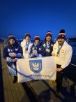 zawodnicy UKS „Delfin” Legionowo  z flagą z herbem powiatu w dłoniach i medalami na szyi