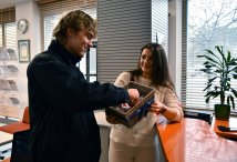 Zdjęcie: mężczyna częstujący się walentynkowym lizakiem podawanym z koszyka przez kobietę.