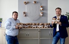 na zdjęciu starosta i członek Zarządu Powiatu, trzymają w rękach misie, misie ustawione również na szafce i przyczepione do herbu