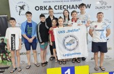 na zdjęciu na podium zawodnicy klubu z trenerem, na tle ścianki, trzymają flagę klubu