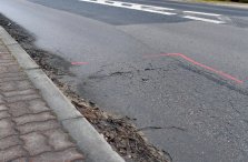 Zdjęcie: uszkodzony fragment jezdni z oznaczonym sprayem miejscem uszkodzenia wymagającym naprawy