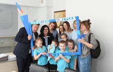 Grupa osób - przedszkolaków oraz dorosłych - pozująca w niebieskiej ramce z napisem: Niebieskie Igrzyska Łączą