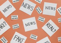 na pomarańczowym tle karteczki z napisem news, fake news oraz real?