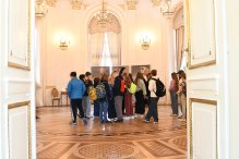 Zdjęcie przedstawia grupę uczniów szkoły podstawowej podczas zwiedzania zabytkowej sali balowej Pałacu w Jabłonnie.