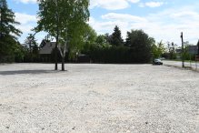 Zdjęcie przedstawia widok na nowo powstaly parking wyłożony tłuczniem betonowym.