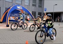 Zdjęcie przedstawia namiot promocyjny WORD Warszawa, na drugim planie po lewej. Na pierwszym planie po prawej osoby jadące na rowerach.