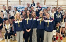 Na zdjęciu grupa zawodniczek z medalami i pucharem w hali sportowej
