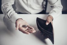 Na zdjęciu otwarty portfel i dłoń z monetami