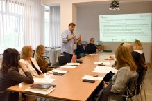 Szkolenie, uczestnicy przy stole, siedzą na krzesław, obok wykładowca