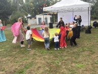 Zdjęcie wykonane w Kompleksie Rekreacyjno-Wypoczynkowym Nieporęt-Pilawa, grupa dzieci uczetniczy w zabawie z kolorowa chustą.