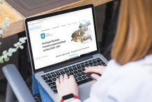 Zdjęcie - widok od tyłu na osobę przacującana lapotopie,m urzedzenie leży na kolanach.