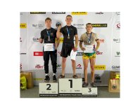 Na zdjęciu trzech młodych mężczyzn stojących na stopniach podium.