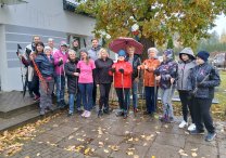 na zdjęciu grupa ludzi z kijami nordic walking, na dworze, ubrani w kurtki