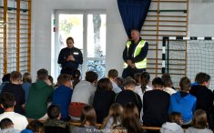 Spotkanie na sali gimnastycznej, dwójka policjantów przemawia do dzieci