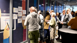 Na zdjęciu widoczni są członkowie warsztatów, którzy stoją przy ścianie za zawieszonymi kartkami