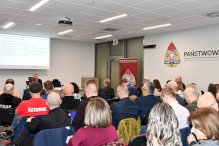 Osoby siedzące i sluchajace prelekcji na sali wykładowej w Komendzie Powiatowej Strazy Pożarnej w Legionowie